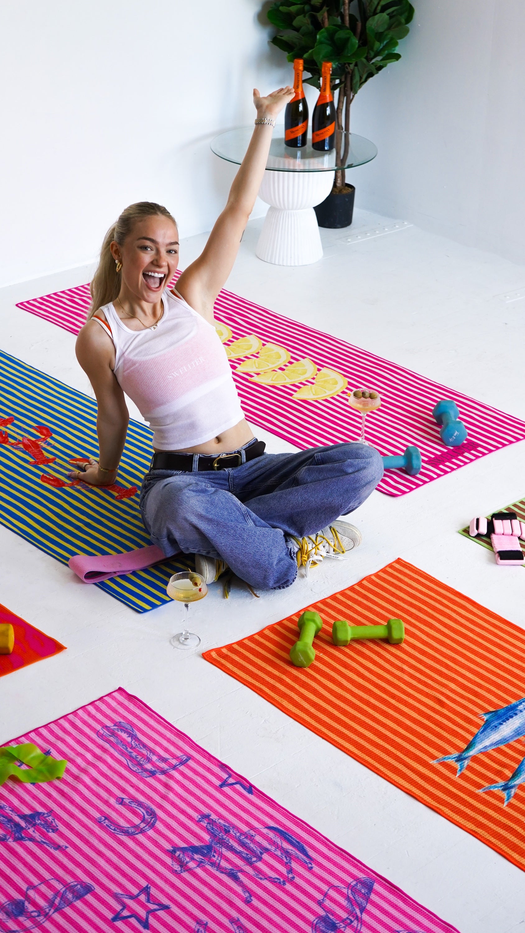 Woman exercising on a colorful mat with various fitness equipment around her.